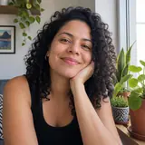 Mulher de cabelos cacheados sorrindo ao lado de pequenos vasos de plantas